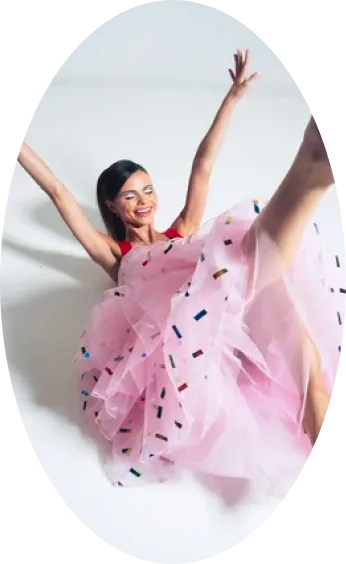 A dancer mid-leap in a pink tulle dress scattered with sequins
